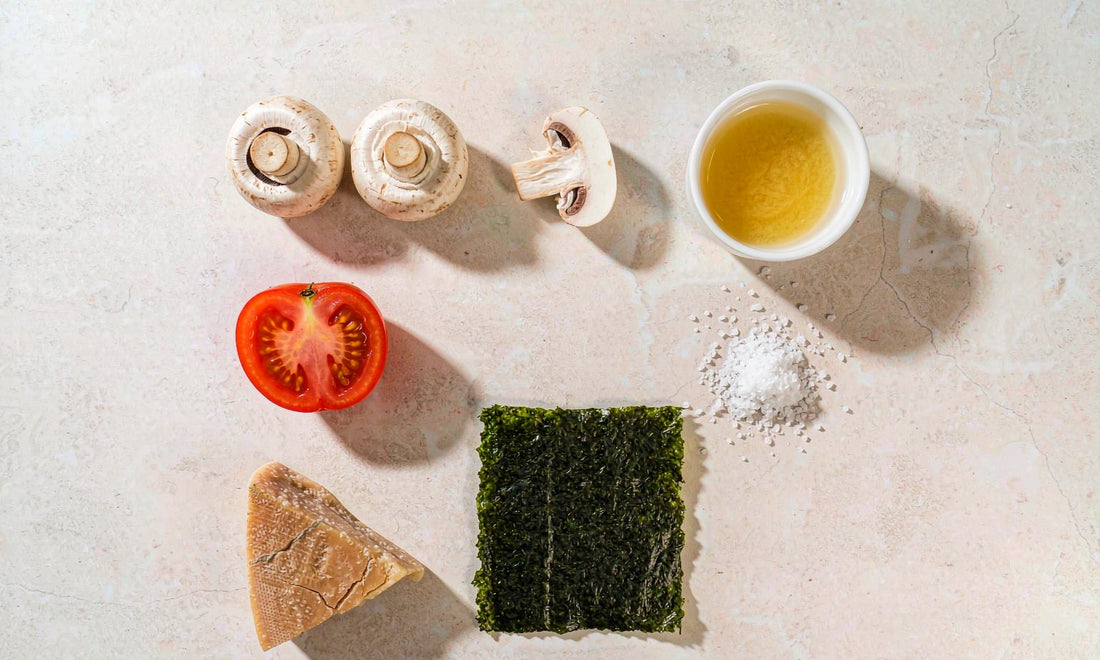 Overhead flat lay of natural umami foods including tomato mushrooms parmesan seaweed and broth
