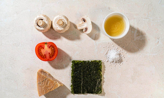 Overhead flat lay of natural umami foods including tomato mushrooms parmesan seaweed and broth