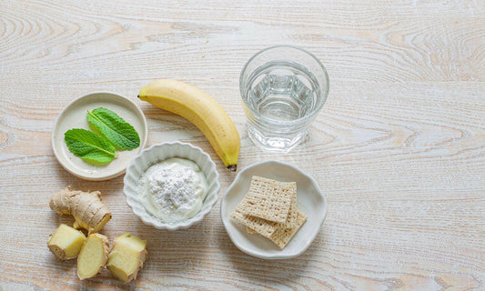 Flat lay of digestion friendly foods with ginger, mint, yogurt, banana, rice crackers and a glass of water
