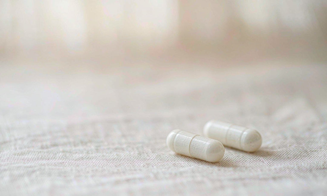 Macro close-up of two white capsules on pale linen fabric, a simple look at supplement form and texture