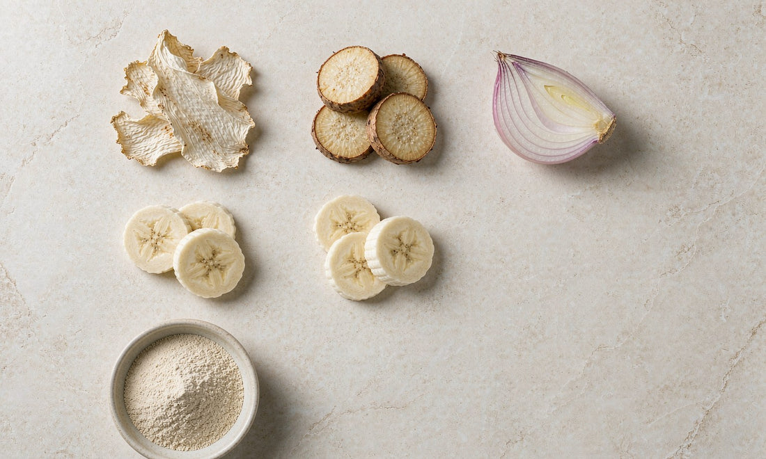 Overhead flat lay of chicory root, Jerusalem artichoke, onion and banana slices on pale stone