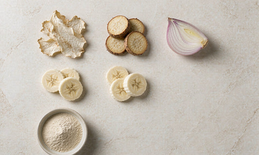 Overhead flat lay of chicory root, Jerusalem artichoke, onion and banana slices on pale stone