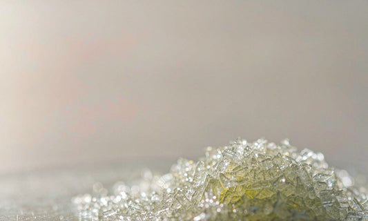 Macro of shimmering pale mineral crystals with fine powder on a glass slide in soft light