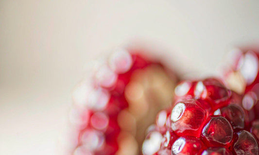 Macro close-up of glistening crimson pomegranate seeds with soft bokeh, a colorful heart friendly fruit