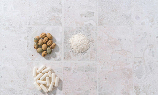White capsules, dried legumes and amino acid powder arranged in a minimal grid on pale stone