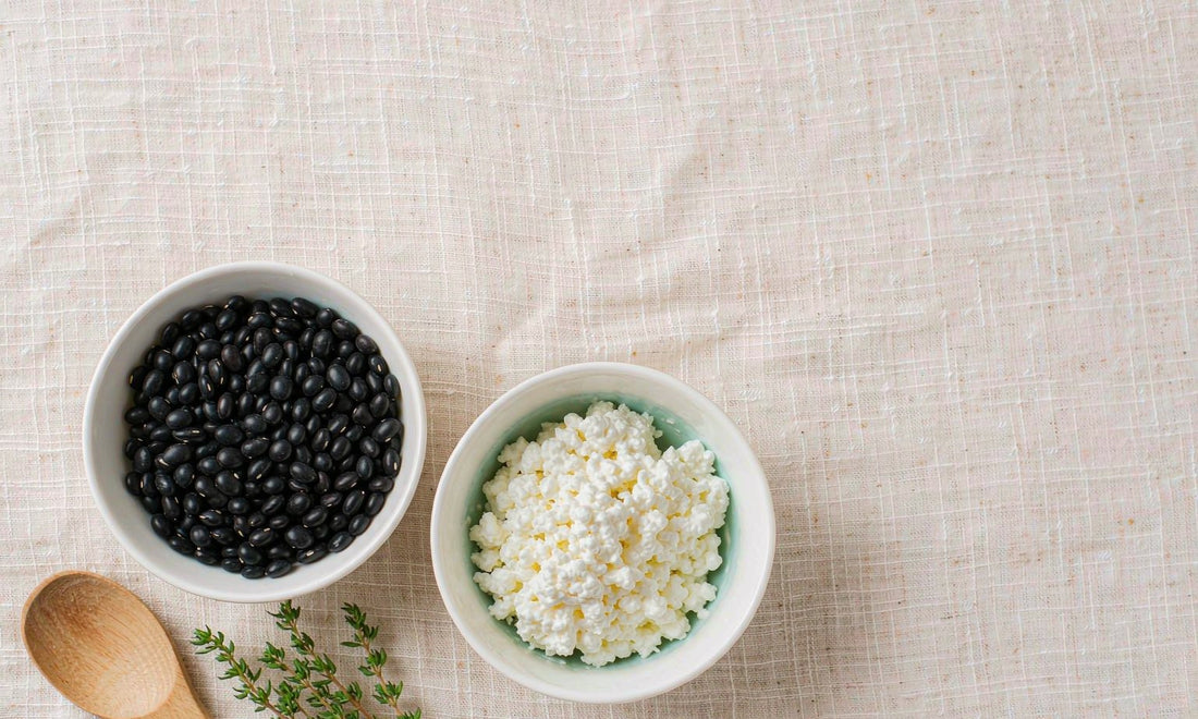 Two ceramic bowls of black beans and cottage cheese side by side on a linen cloth
