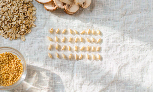Overhead flat-lay of oats, mushrooms and grains arranged on pale linen in soft daylight