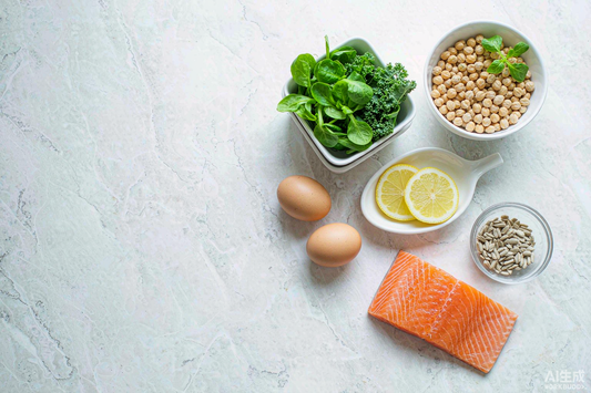 Overhead flat lay of B vitamin rich foods with eggs leafy greens salmon citrus and legumes on marble