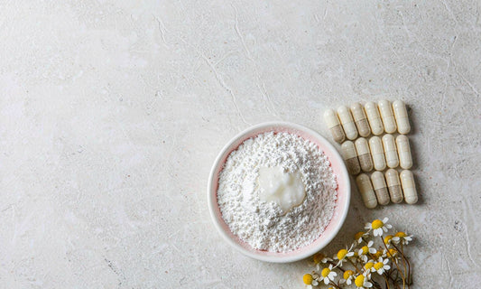 White mineral powder and capsules arranged beside chamomile flowers on a stone surface