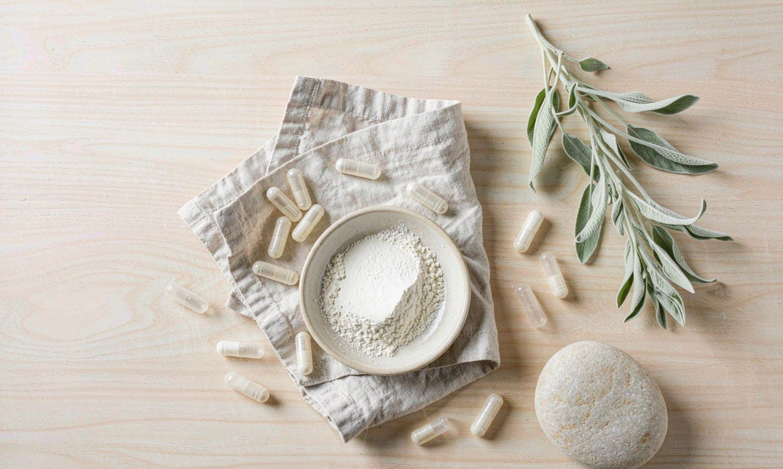 Fine mineral powder in a ceramic dish with capsules and sage leaves arranged on pale linen
