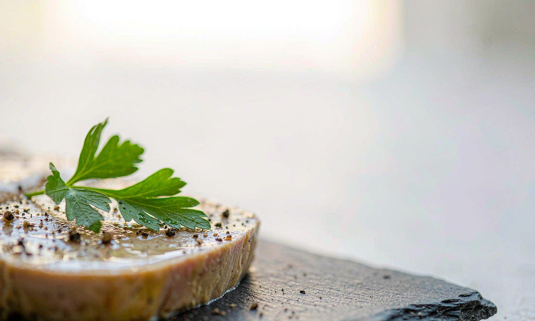 Macro close up of a nutrient dense grass fed pate slice with parsley and cracked pepper on a slate board
