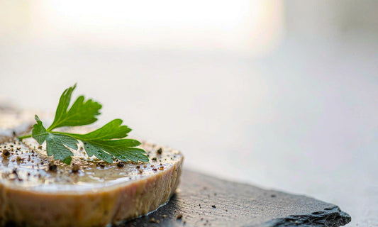 Macro close up of a nutrient dense grass fed pate slice with parsley and cracked pepper on a slate board