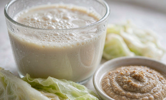 Macro close-up of a glass of kefir with sauerkraut leaves and a small dish of miso