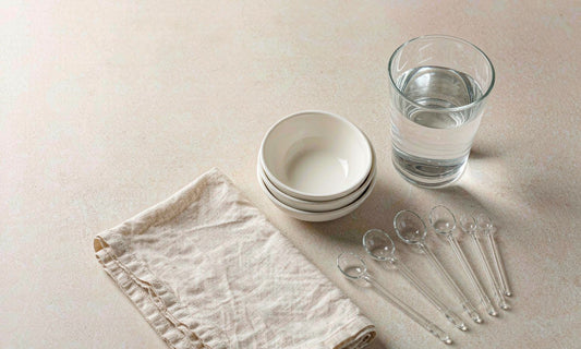 Measuring spoons, ceramic bowls and a glass of water laid out neatly on a beige counter to show careful portioning