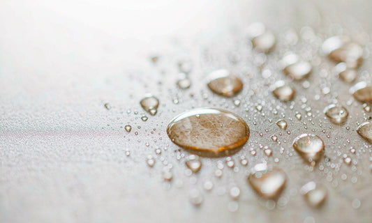 Macro photograph of amber droplets and fine powder on white ceramic suggesting enzyme activity