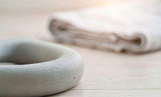 Macro close-up of a matte kettlebell handle on a pale wooden floor with a folded towel in soft light