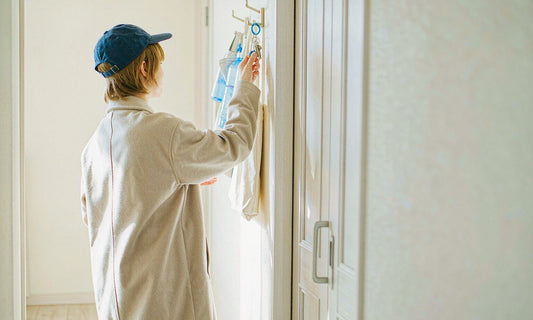 Person reaching for keys by the front door beside a water bottle and tote bag in soft morning light