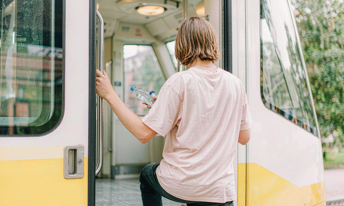 Person boarding a bright commuter train with a water bottle, keeping a supplement routine on the go