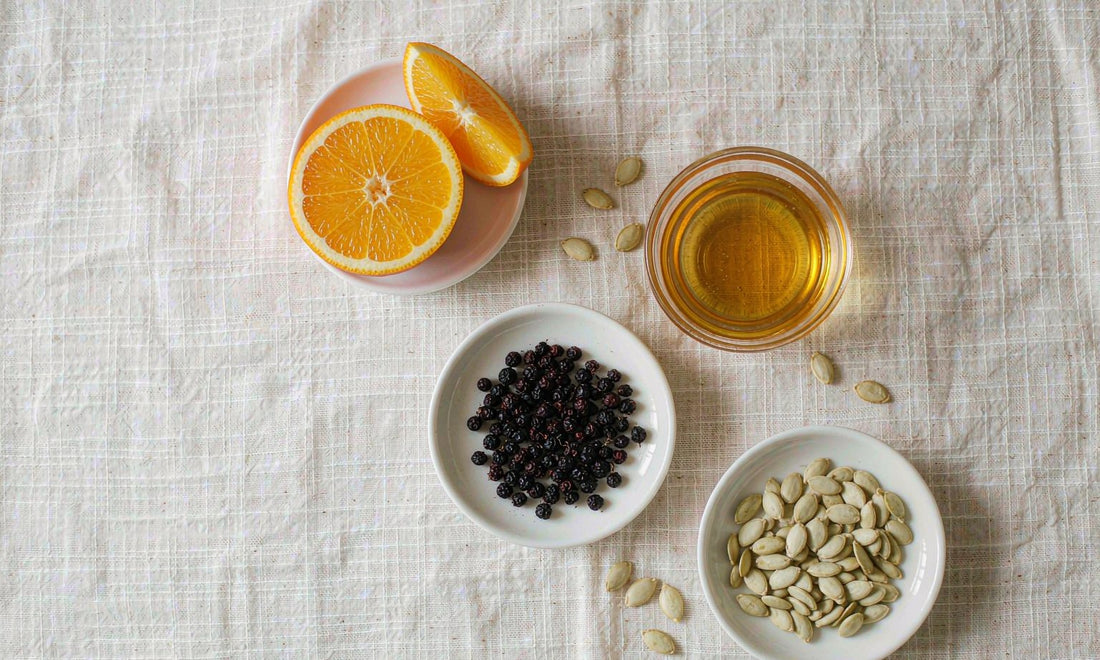 Flat lay of orange slices, elderberries, honey and pumpkin seeds, classic immune supporting ingredients