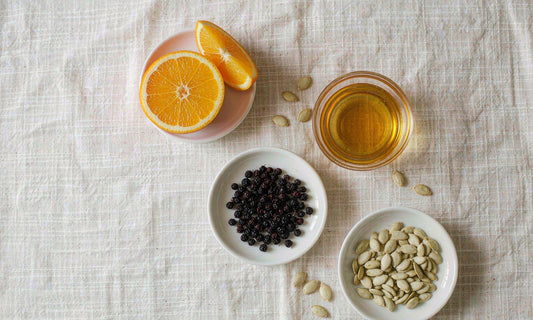 Flat lay of orange slices, elderberries, honey and pumpkin seeds, classic immune supporting ingredients