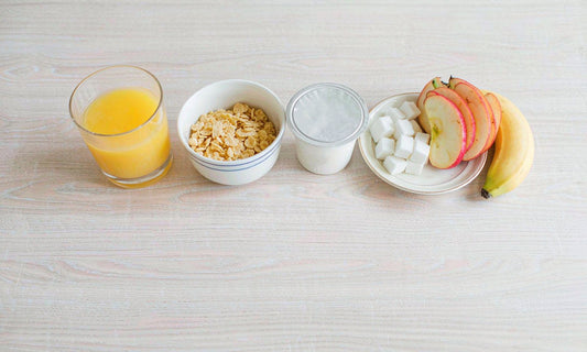 Overhead flat lay of a family breakfast with orange juice, cereal, yogurt, sugar cubes and fresh fruit