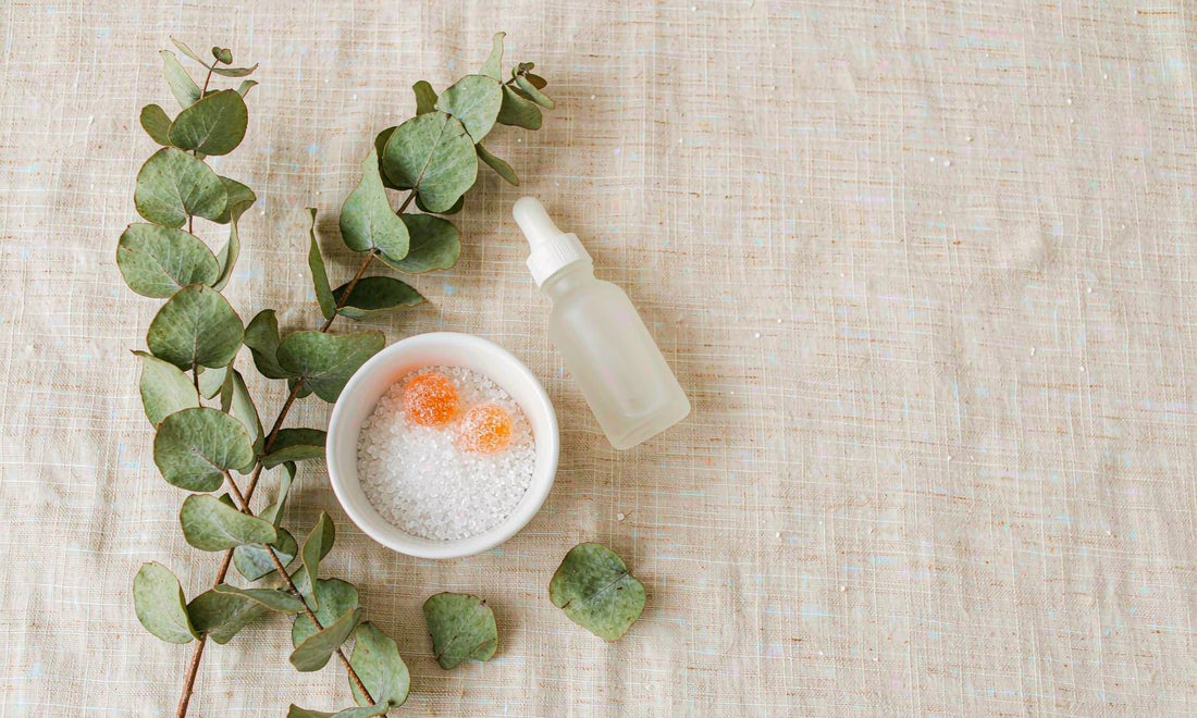 Flat lay of white crystalline L-lysine amino acid powder in a ceramic bowl with orange gummies and a dropper bottle on cream linen