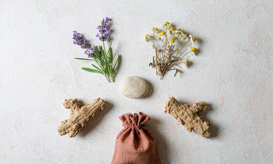 Calm ingredient flat lay of ashwagandha root, lavender and chamomile arranged on pale stone
