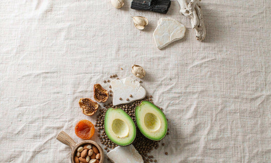 Overhead arrangement of figs, lentils, avocado and pale mineral stones on beige linen